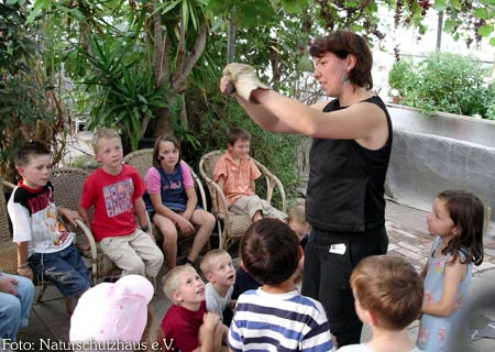 Referentin zeigt versammelten Kindern eine lebende Fledermaus